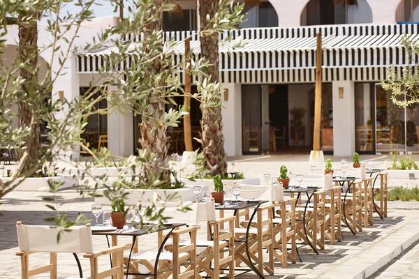 Außenbereich des Grecotel Casa Marron Hotels mit Tisch, Stühlen und Pflanzen.