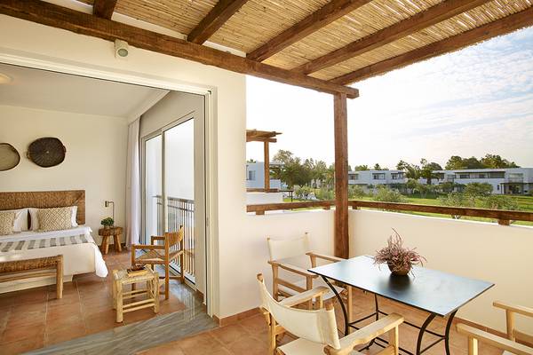 Balkon des Grecotel Casa Marron mit Bett, Tisch und Blick auf die Landschaft.