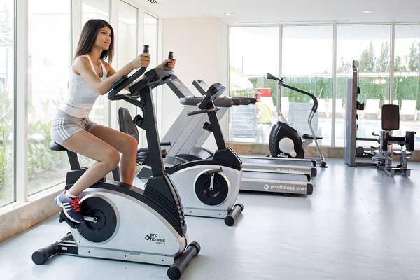 Frau im Roma Beach Resort & Spa Fitnessstudio auf einem Fahrrad