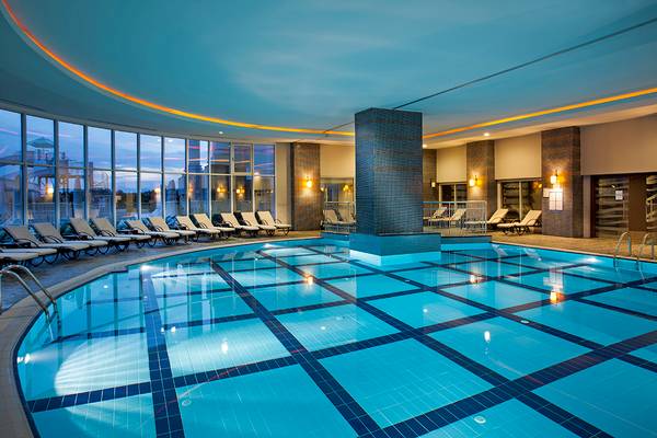 Innenpool des Roma Beach Resort & Spa mit Lounge-Sesseln und Glaswänden.