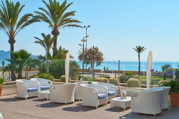 Terrasse des Hipotels Hipocampo Playa mit Blick auf das Meer und Palmen.