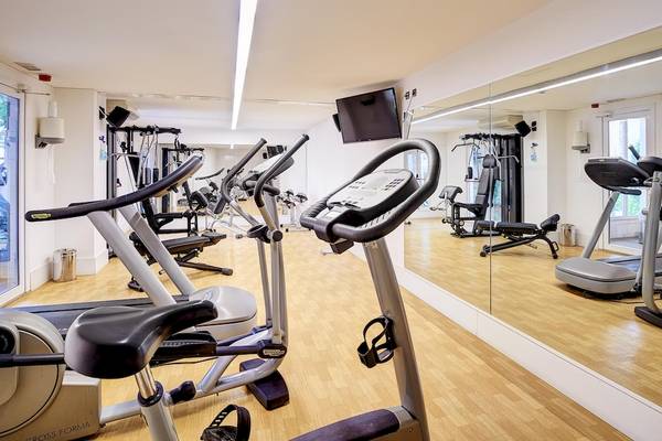 Fitnessraum im Hipotels Hipocampo Playa mit diversen Trainingsgeräten und einem großen Spiegel.