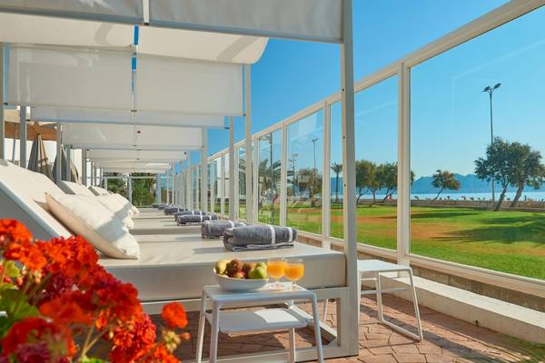 Terrasse des Hipotels Hipocampo Playa mit weißen Liegen und Ausblick auf das Meer.