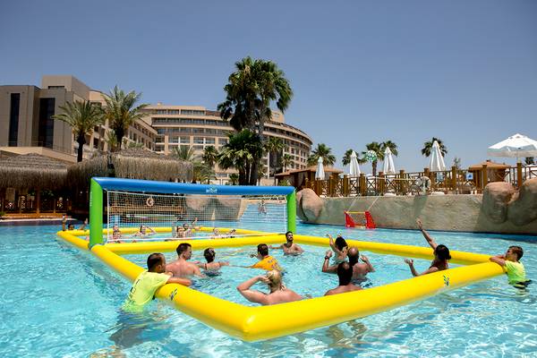 Gruppe von Erwachsenen spielt Volleyball im Pool des Fame Residence Lara & Spa Hotels.