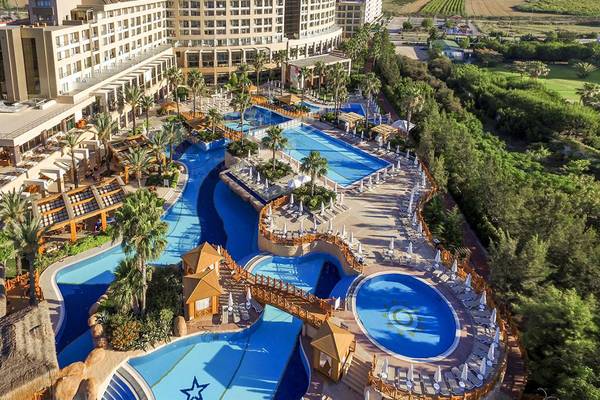 Luftaufnahme des Fame Residence Lara & Spa Hotels mit mehreren Swimmingpools und Sonnenliegen