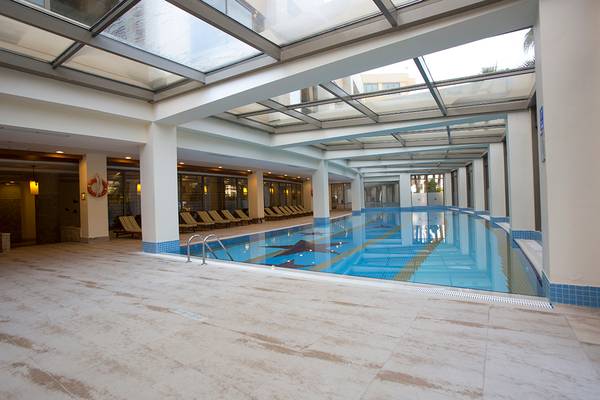 Innenpool im Fame Residence Lara & Spa mit Glasdach und leeren Sonnenliegen