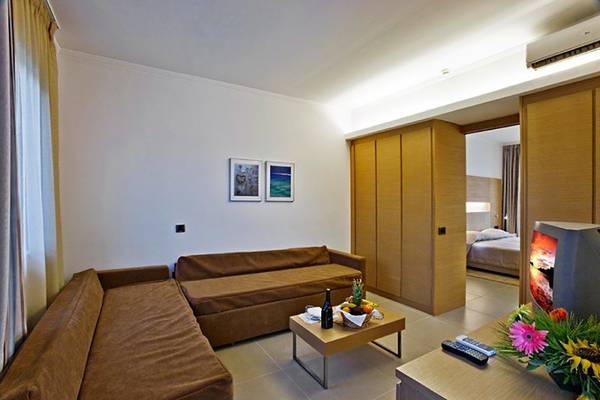 Loungebereich im Hotelzimmer mit zwei Sofas, einem Tisch, einem Fernseher und einem Bett im Hintergrund.