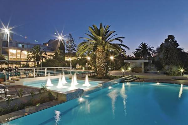 Der Pool des Caravia Beach Hotel bei Nacht mit Springbrunnen und Beleuchtung.