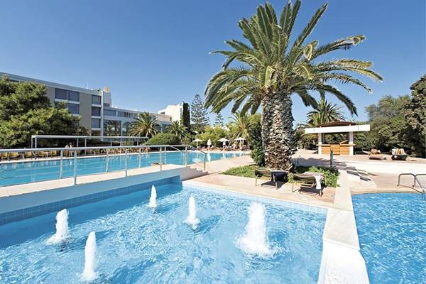 Außenbereich des Caravia Beach Hotel mit Swimmingpool und Palme.