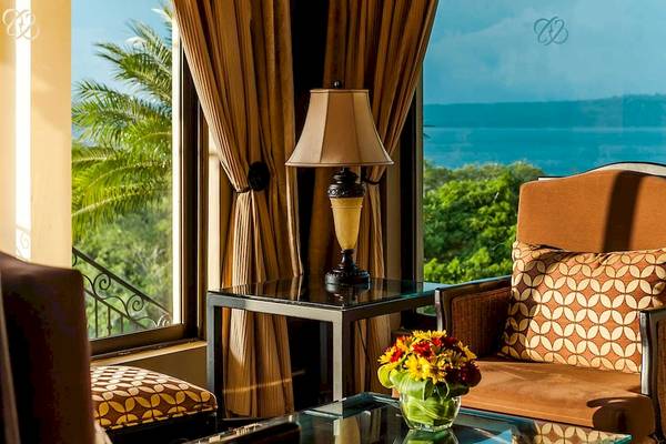 Hotelzimmer mit Meerblick, Lampe auf Tisch und Sessel mit Blumen