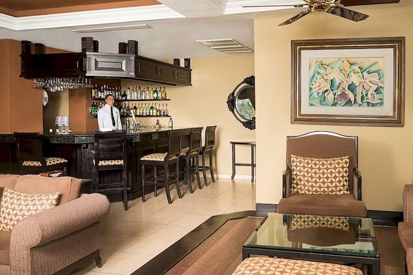 Der Barbereich des Occidental Papagayo Hotels mit einem Barkeeper und kunstvollen Wanddekorationen.