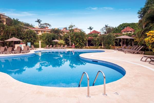 Außenpoolbereich des Occidental Papagayo Hotels mit Sonnenliegen und Sonnenschirmen.