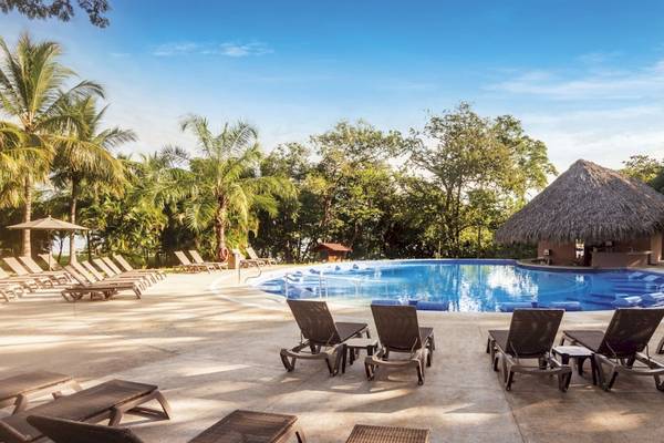 Außenpool am Abend im Occidental Papagayo Hotel mit Sonnenliegen und Blick auf Palmen und Bäume