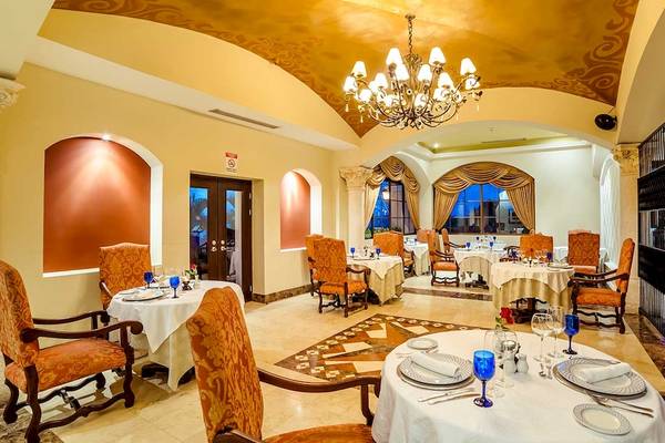 Innenansicht des Restaurants im Occidental Papagayo Hotel mit gedeckten Tischen und Stühlen, einer großen Deckenleuchte und großen Fenstern.