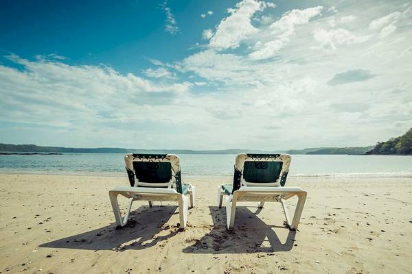 Zwei Sonnenliegen stehen am Strand des Occidental Papagayo Hotels mit Blick auf das Meer.