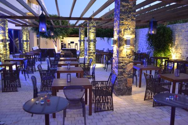 Terrasse des Island Hotels auf Kreta bei Nacht mit beleuchteten Tischen und Stühlen.