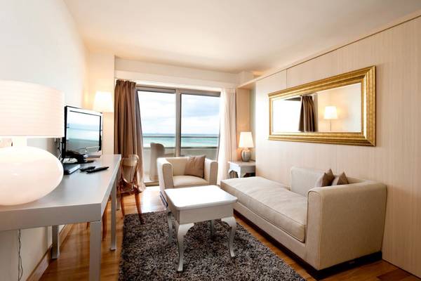 Wohnzimmer des Insel Hotels auf Kreta mit Meerblick, großer Fensterfront, moderner Einrichtung und blauem Himmel.