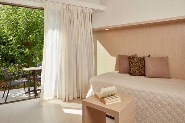 Schlafzimmer im Island Hotel auf Kreta mit Balkon, Tisch und Stühlen.