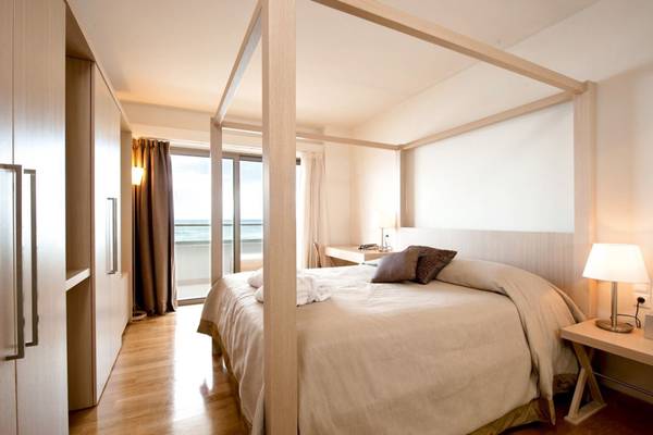 Schlafzimmer im The Island Hotel auf Kreta mit Himmelbett, Meerblick und moderner Einrichtung.