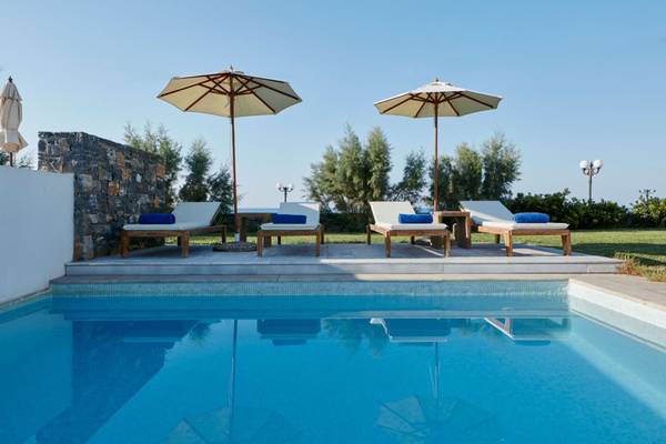 Ein Swimmingpool mit vier Lounge-Liegen und Sonnenschirmen am The Island Hotel auf Kreta.