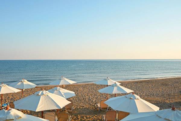 Strand des Island Hotels auf Kreta mit vielen weißen Sonnenschirmen am Meer