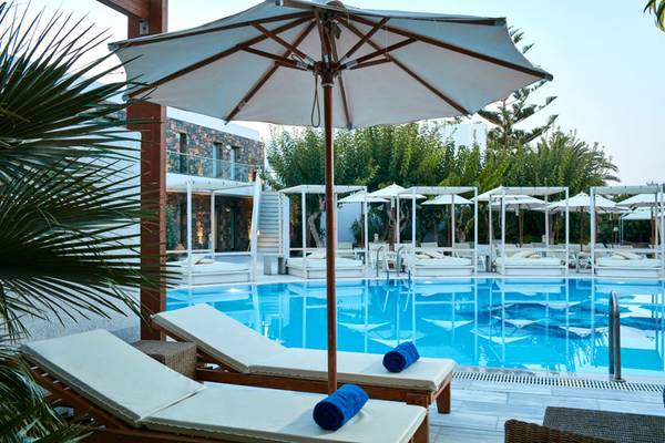 Außenpoolbereich des Island Hotels auf Kreta mit Sonnenliegen und Schirmen.