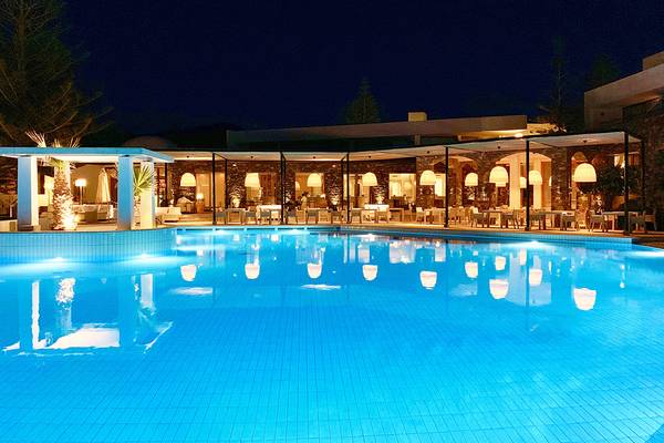 Ein Swimmingpool bei Nacht im The Island Hotel in Kreta mit leuchtenden Lichtern.