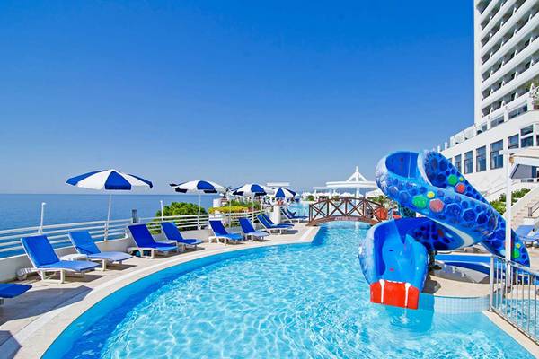 Poolbereich des KoruMar Hotel De Luxe mit Wasserrutsche und Sonnenliegen