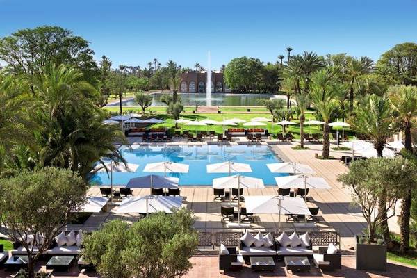 Barcelo Palmeraie Hotel mit Swimmingpool und Palmen im Freien.