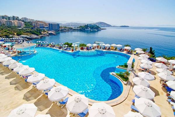 Aussenpool des KoruMar Hotel De Luxe mit vielen Sonnenschirmen und Liegen am Meer