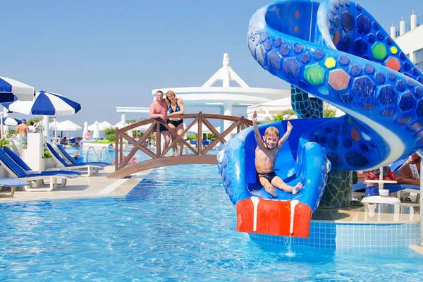 Kind rutscht auf einer farbigen Wasserrutsche im Schwimmbad des KoruMar Hotel De Luxe