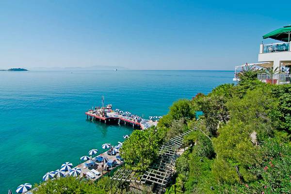 Ausblick auf das Meer vom KoruMar Hotel De Luxe mit einer roten Pier und vielen Sonnenschirmen.