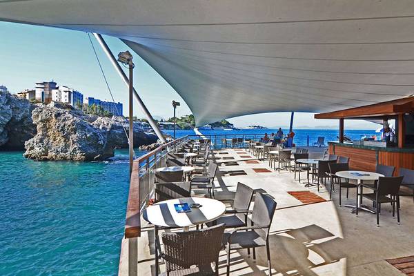 Terrasse des KoruMar Hotel De Luxe mit Blick auf das Meer und eine Klippe.