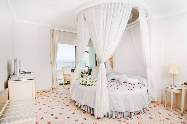 Schlafzimmer im KoruMar Hotel De Luxe mit Bett, Rosenblättern und Meerblick.