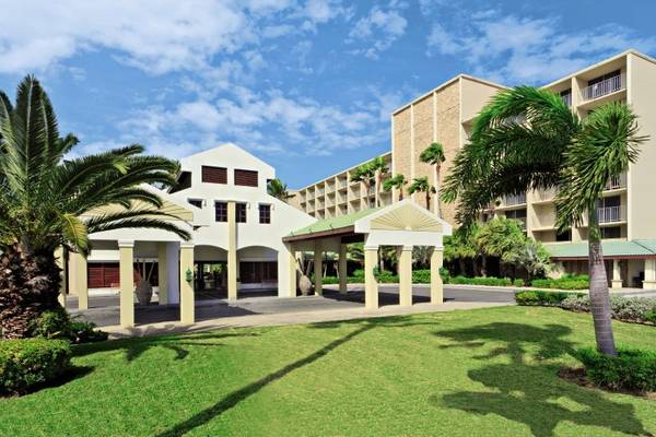 Außenansicht des Holiday Inn Resort Aruba mit Gebäuden, Palmen und Rasen
