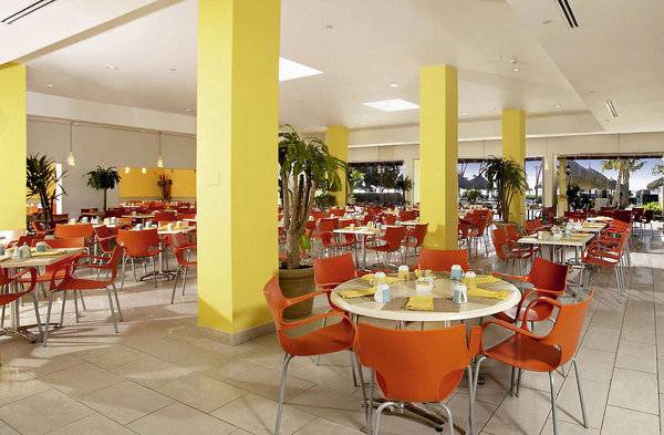 Restaurant des Holiday Inn Resort Aruba mit orangen Stühlen und Tischen.