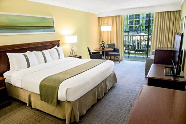Hotelzimmer im Holiday Inn Resort Aruba mit einem großen Bett, Tisch, Stühlen und Fernseher.