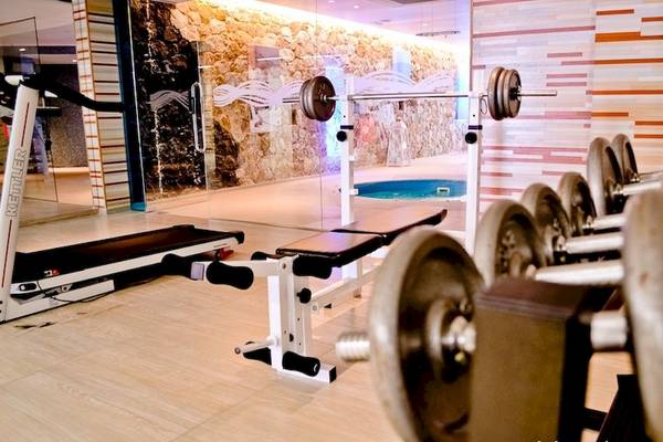 Fitnessbereich im La Mer Deluxe Hotel & Spa mit Laufband, Hantelbank und freien Hanteln.