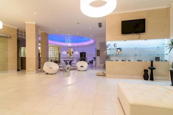 Lobby des La Mer Deluxe Hotel & Spa mit weißen Möbeln, einer Fernsehwand und blauer Beleuchtung.