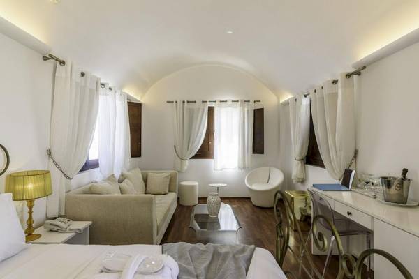 Innenansicht eines Schlafzimmers im La Mer Deluxe Hotel & Spa mit weißen Möbeln und Holzboden.