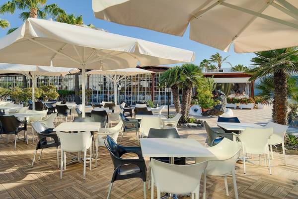 Außenbereich des H10 Suites Lanzarote Gardens Hotels mit vielen Tischen und Stühlen unter Schirmen.