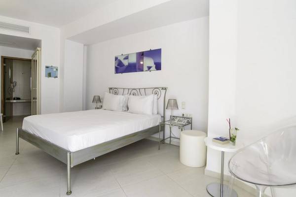 Schlafzimmer im La Mer Deluxe Hotel & Spa mit weißem Bett, Kopfkissen, Nachttisch und transparentem Stuhl.