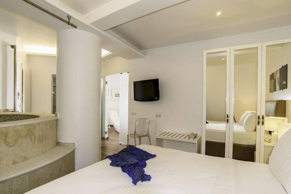 Innenansicht eines Zimmers im La Mer Deluxe Hotel & Spa mit einem Bett, Fernseher und Badewanne.