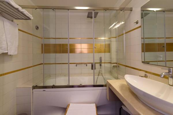 Badezimmer im La Mer Deluxe Hotel & Spa mit Glasdusche, Badewanne und Waschbecken.