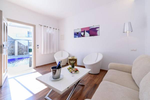 Wohnbereich des La Mer Deluxe Hotel & Spa mit Swimmingpool, weißer Einrichtung und Obstteller auf dem Tisch.