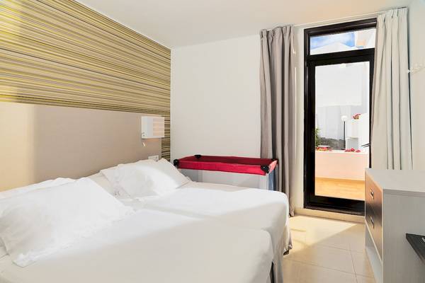 Doppelbettzimmer im H10 Suites Lanzarote Gardens mit hellem Interieur, zwei Betten, einem Balkon und einer Terrasse.