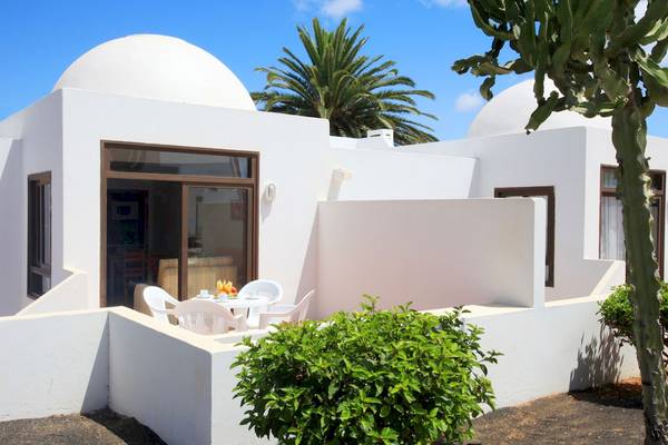 Terrasse des H10 Suites Lanzarote Gardens Hotels mit weißem Tisch und Stühlen unter blauem Himmel.