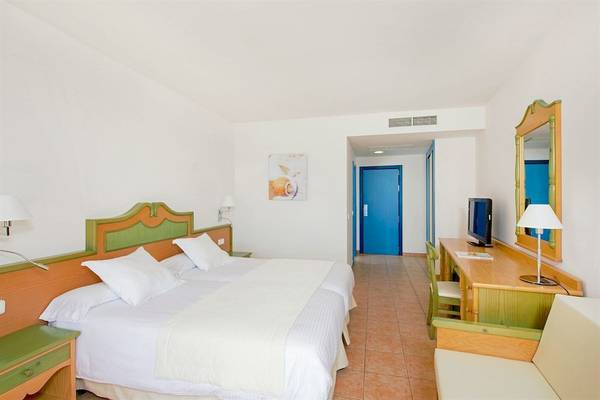 Innenansicht eines Hotelzimmers im Iberostar Playa Gaviotas mit zwei Betten, Schreibtisch und Spiegel.