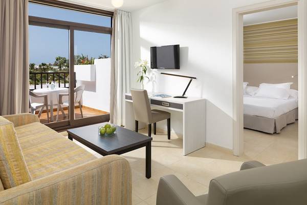 Innenansicht der Suite im H10 Suites Lanzarote Gardens mit Wohnzimmer, Esstisch und Terrasse.