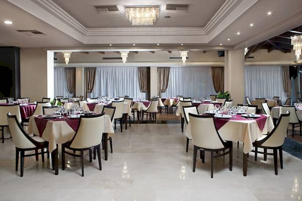 Innenansicht des Restaurants im Olympia Golden Beach Resort mit gedeckten Tischen und Stühlen.